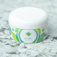 A tub of Eco Chic Movement's all natural body butter sits on a white and gray granite countertop