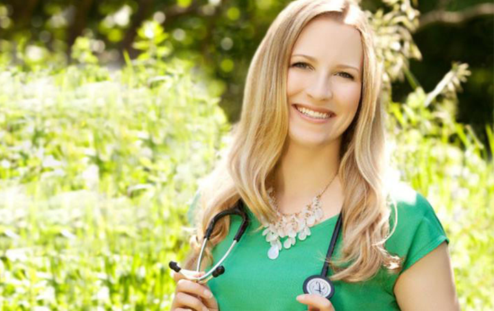 A naturopathic doctor in Ontario, Canada, Dr. Alexis Reid stands in front of green plants wearing a green top and stethoscope