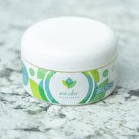 A tub of Eco Chic Movement's all natural body butter sits on a white and gray granite countertop