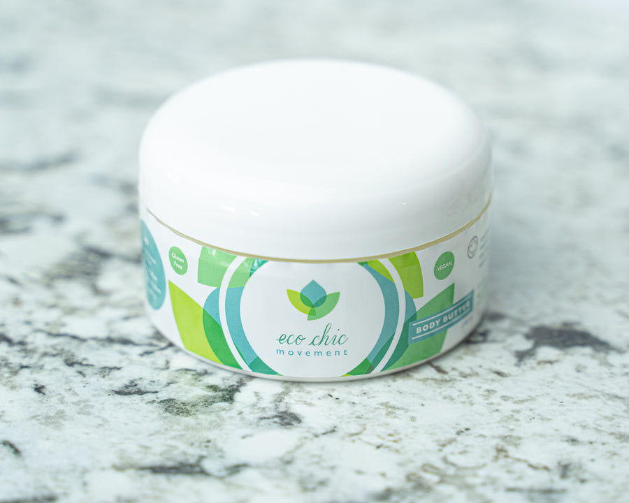 A tub of Eco Chic Movement's all natural body butter sits on a white and gray granite countertop