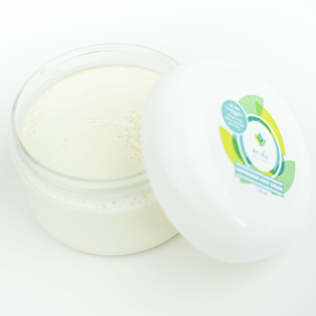 An open jar of non toxic peppermint foot cream sits on a white table
